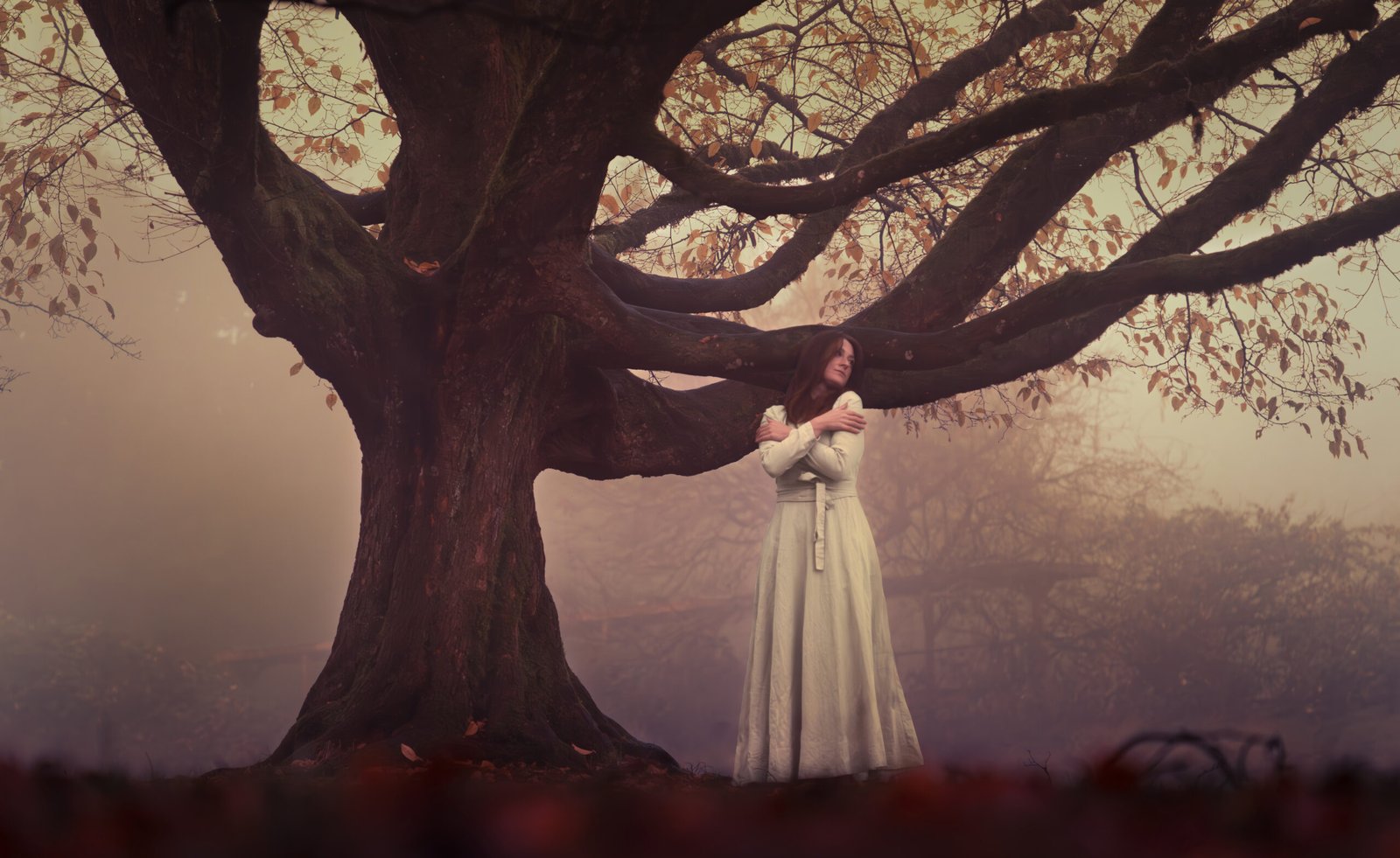 woman with cream dress standing next to a big tree in a foggy day in Vancouver