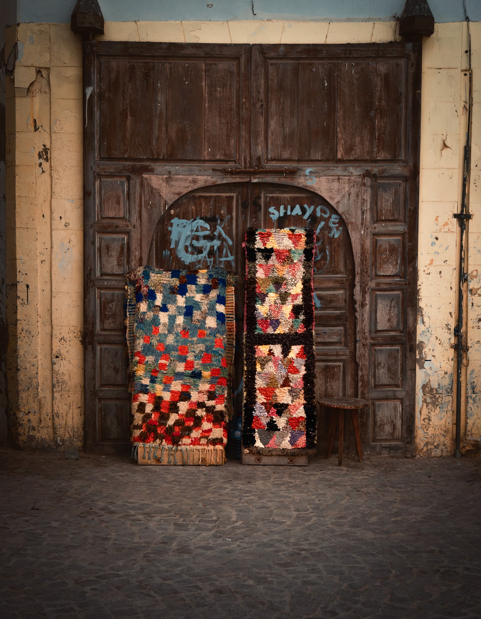 street photography in median in Essaouira in Morocco handmade rugs leaning on an ancient door on the street