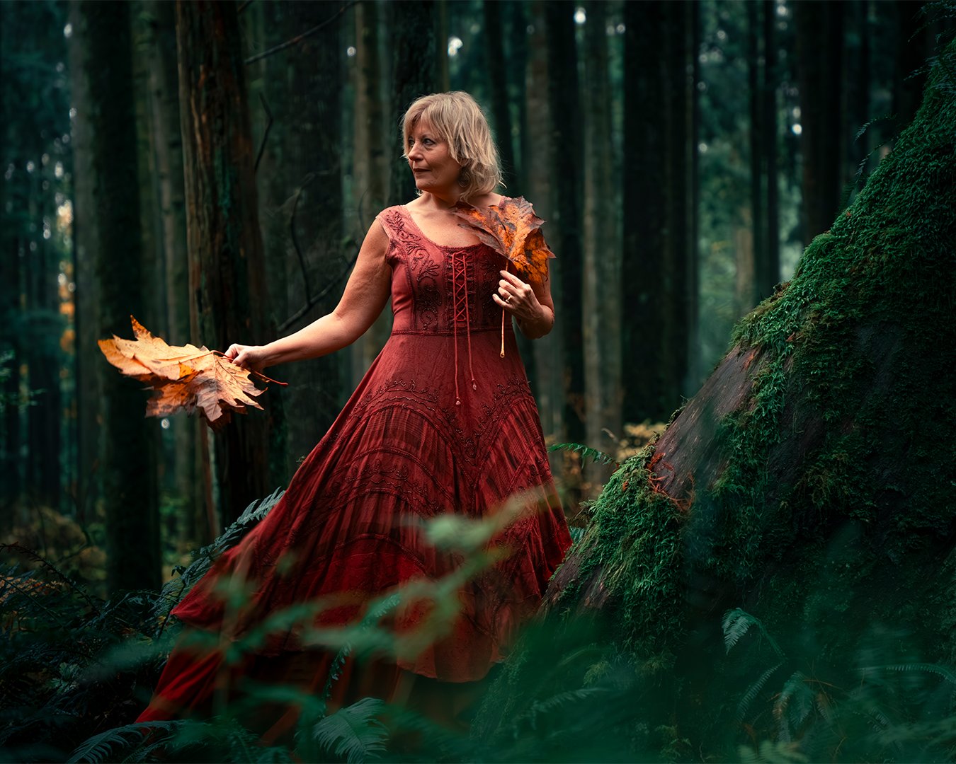 solo portrait in nature woman wearing a red dress posing naturally in the forest in british columbia for a professional photographer in Vancouver