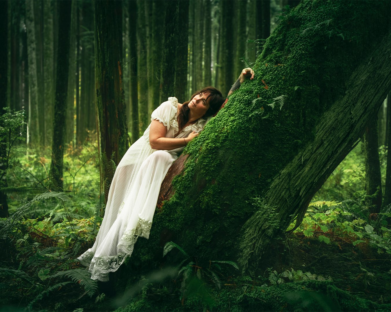 solo portrait in nature woman wearing a white dress posing naturally in the green forest for a professional photographer in Vancouver